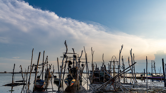 A long-tailed boat is laid on the boat rack while off-duty. The owner shall take his boat off the rack into the lagoon, to feed his fish or fix the equipment. This fishing village is located in Songkhla of south Thailand
