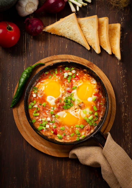istock fried eggs with stewed tomatoes , cast iron pan , on a wooden table,top view , rustic, vertical 1277163203