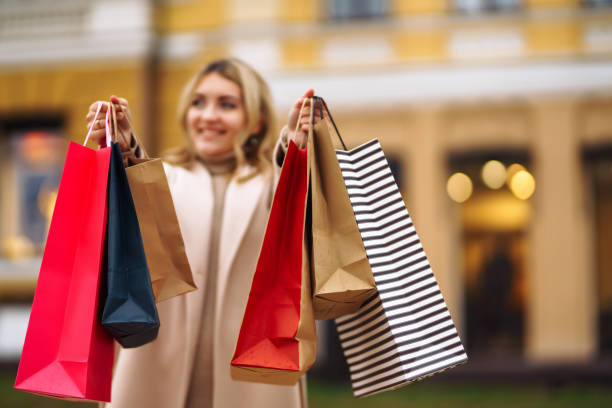 istock Young woman holds out multi-coloured bags with purchase 1277169159