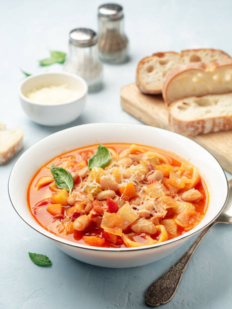 zuppa italiana di minestrone con parmigiano e basilico su sfondo di cemento blu - minestrone foto e immagini stock