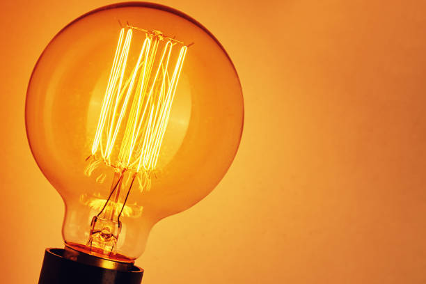 istock Vintage light bulb on yellow background, closeup. Glowing edison bulb 1277170494