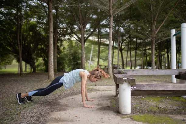 Asia Chinese women exercising burpees Jumping training in public park.