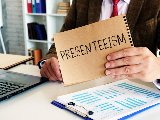 istock Presenteeism concept. The employee holds a notepad with the inscription. 1277178431