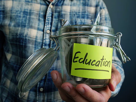 Jar with dollars and the inscription Education. The guy keeps his college savings.