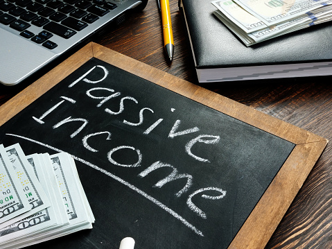 Passive income inscription on the board and a bundle of bills.