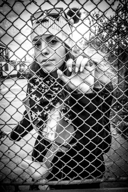 istock Female Looks Through A Fence 1277181079