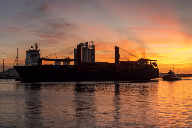 istock Cargo ship arrives at dawn with tugboat 1277182569