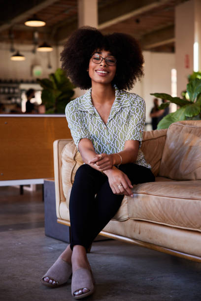 istock Smiling young woman sitting on a sofa in a cafe 1277183859