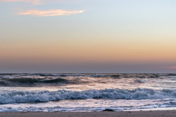 istock Sunset sky with stormy glossy waves on sea shore 1277184077