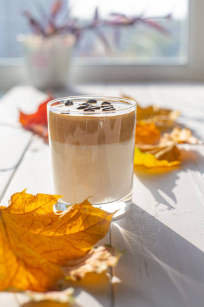 istock Traditional Korean caffeinated milk drink, Dalgona coffee in a glass with coffee beans on white boards, window. 1277184759