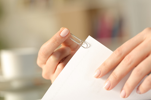 Primer plano de las manos de una mujer poniendo un clip de papel en una hoja photo