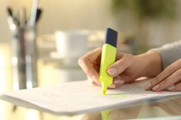 Woman hand underlining text on document with marker