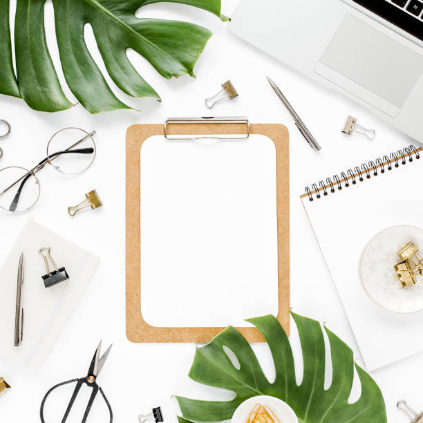 istock Home office workspace mockup with laptop, tropical leaves Monstera, clipboard, notebook and accessories on white background. Flat lay, top view 1277186743