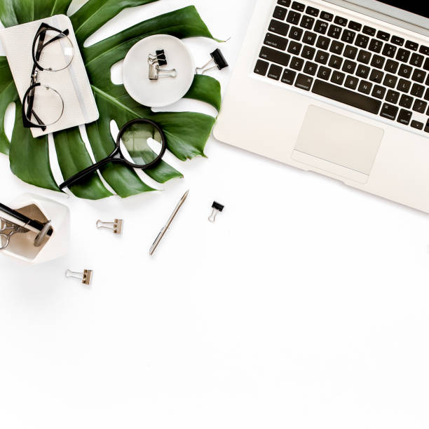 istock Home office workspace mockup with laptop, tropical leaves Monstera, clipboard, notebook and accessories on white background. Flat lay, top view 1277186809