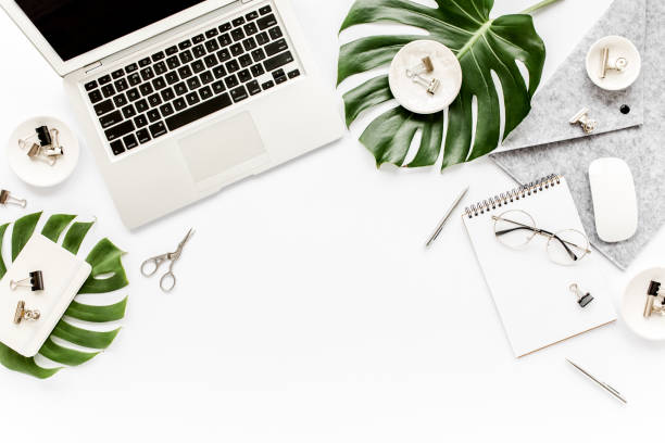 istock Home office workspace mockup with laptop, tropical leaves Monstera, clipboard, notebook and accessories on white background. Flat lay, top view 1277187825