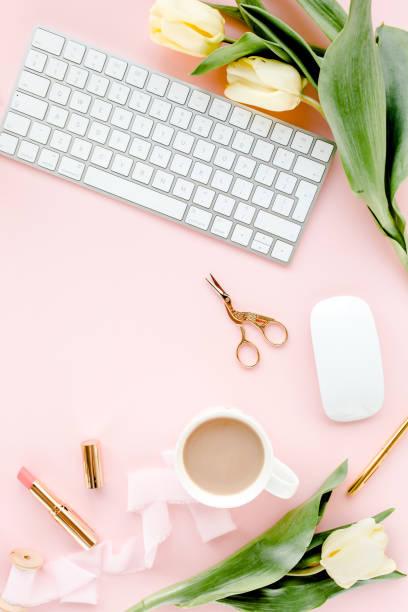 istock Female workspace with computer, tulip flowers bouquet, golden accessories, diary, on pink background. Flat lay women's office desk. Top view 1277187908