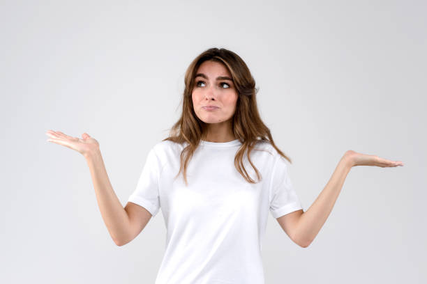 istock Puzzled female with long hair dressed casually, standing in confusion, shrugs shoulders as does not know answer, being clueless and uncertain. Life perception and attitude concept. Isolated on white background 1277188113