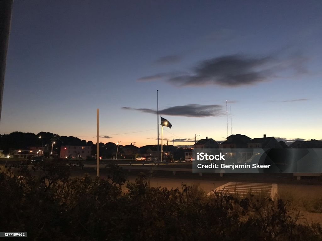 An American Flag at half mast Sunset An American flag at half mast for Ruth Bader Ginsberg  illuminated by a Streetlight with dark clouds overhead. Ruth Bader Ginsburg Stock Photo