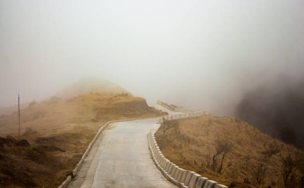 istock paved mountain road through valley disappearing into mist or fog. 1277190223