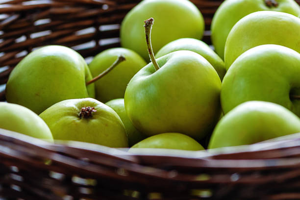 green apples freshly picked in wicker basket, close up
