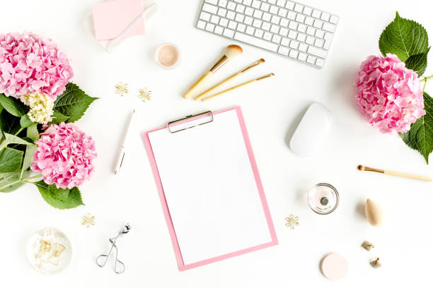 istock Stylized women's desk. Workspace with clipboard, computer, bouquet hydrangea, accessories on white background. Flat lay. Top view 1277194144