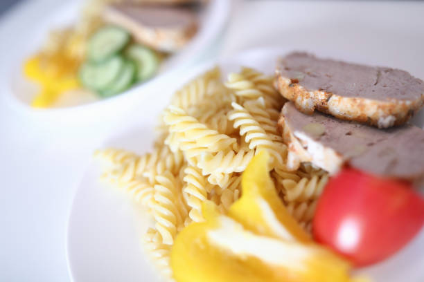 Close-up of delicious breakfast. Pasta cucumber tomato slices of meat and fresh pepper. Yummy portion for couple served on white plate. Healthy eating and food concept