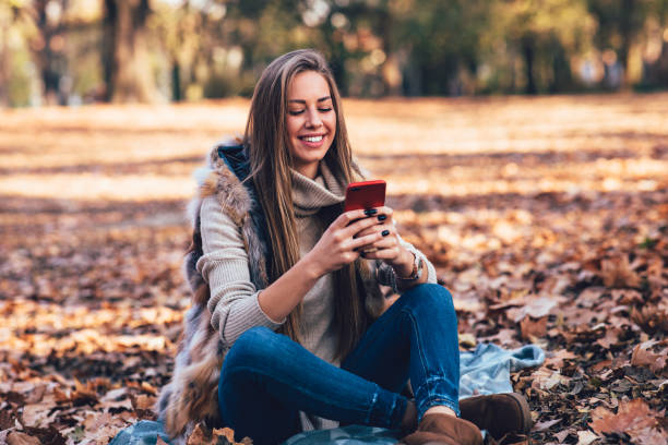 istock Young woman in the park using smartphone  and laughing 1277195674