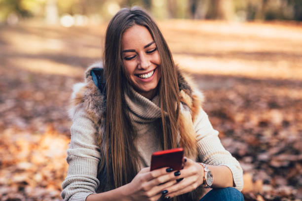 istock Young woman in the park using smartphone  and laughing 1277195710