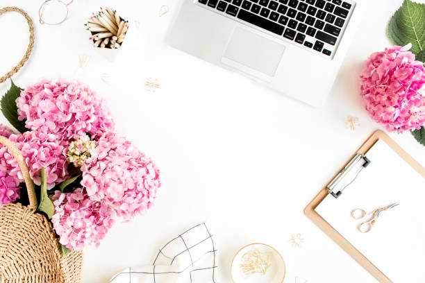 istock Workspace with clipboard, laptop, bouquet hydrangea, accessories on white background. Stylized women's desk. Flat lay. Top view 1277196363