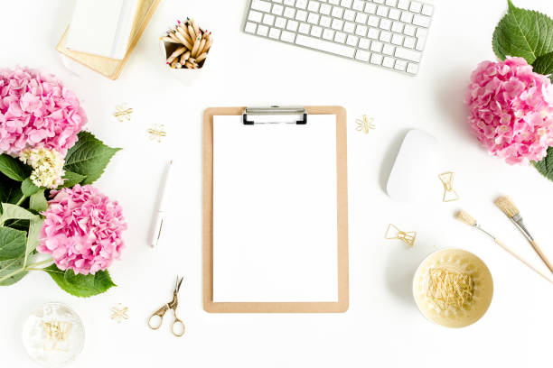istock Stylized women's desk. Workspace with clipboard, computer, bouquet hydrangea, accessories on white background. Flat lay. Top view 1277196442