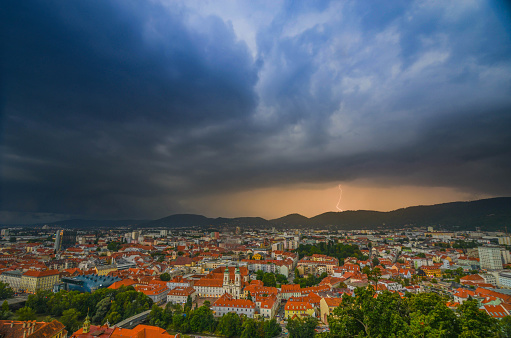 Lightning storm with dramatic clouds over the city of Graz, with Mariahilfer church and historic buildings, in Styria region, Austria