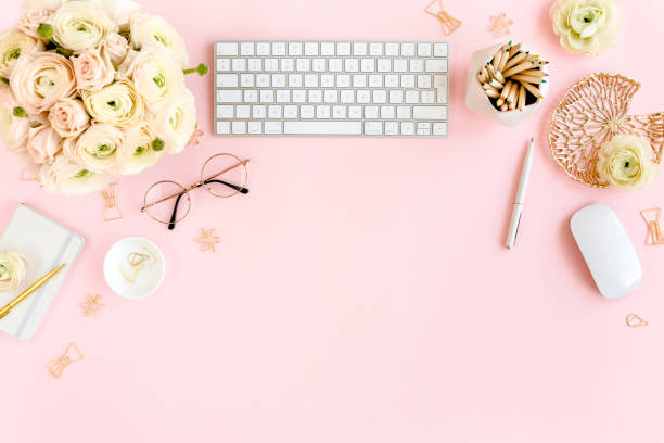 istock Stylized, pink women's home office desk. Workspace with computer, bouquet ranunculus and roses, clipboard on pink background. Flat lay. Top view 1277196771