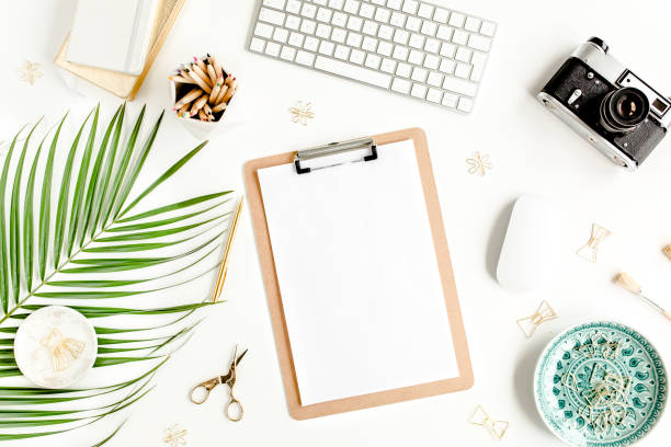 istock Flat lay home office desk. Female workspace with computer, clipboard, tropical palm leaves, accessories on white background. Top view 1277197237
