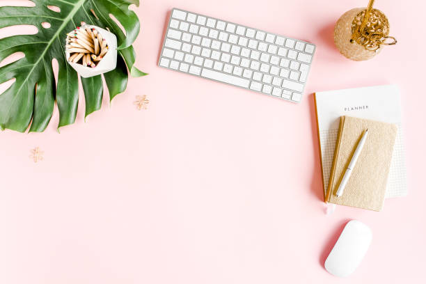 istock Flat lay home office desk. Female workspace with computer, tropical palm leaves Monstera, accessories on pink background. Top view background 1277198082