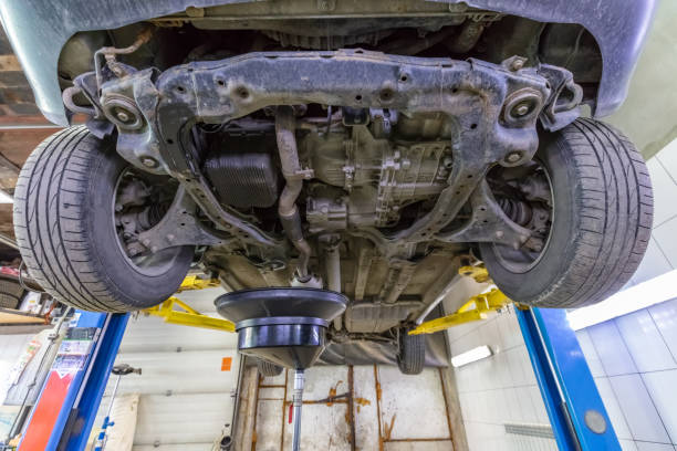 istock Draining engine oil from car lifted on hydraulic lift in workshop during routine service. 1277198251