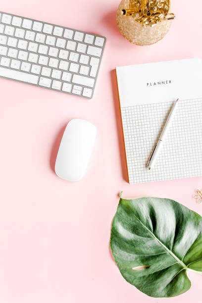 istock Flat lay home office desk. Female workspace with computer, tropical palm leaves Monstera, accessories on pink background. Top view background 1277198501