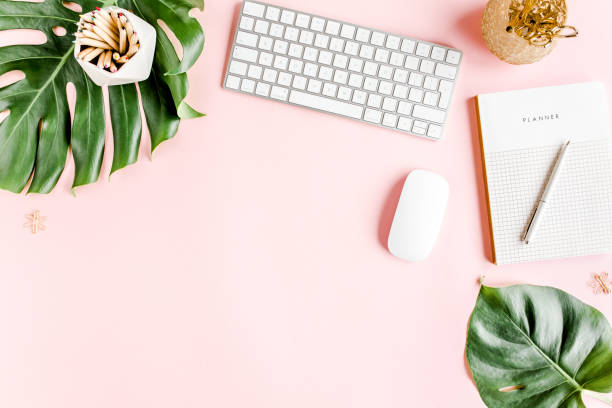 istock Flat lay home office desk. Female workspace with computer, tropical palm leaves Monstera, accessories on pink background. Top view background 1277198564