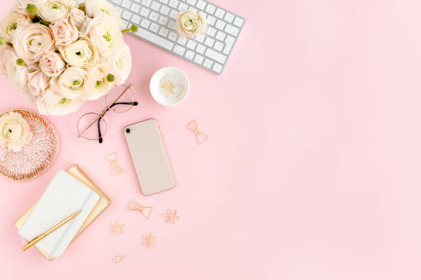istock Stylized, pink women's home office desk. Workspace with computer, bouquet ranunculus and roses, phone on pink background. Flat lay. Top view 1277198627