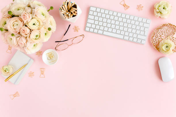 istock Stylized, pink women's home office desk. Workspace with computer, bouquet ranunculus and roses, clipboard on pink background. Flat lay. Top view 1277198748