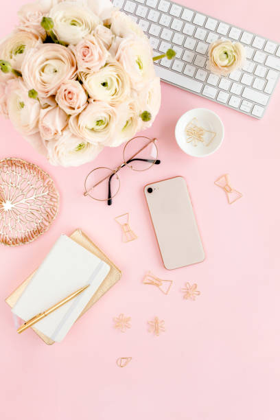 istock Stylized, pink women's home office desk. Workspace with computer, bouquet ranunculus and roses, phone on pink background. Flat lay. Top view 1277198783