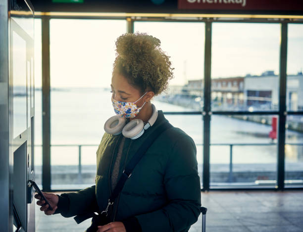 Who's got time to be fumbling for coins? Shot of a masked young woman using a smartphone at the parking meter in a subway station contactless airport stock pictures, royalty-free photos & images