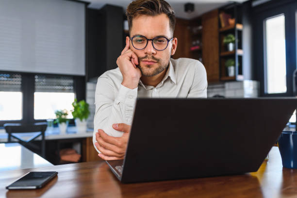 istock Young handsome man working from home, sitting in front of laptop computer having meeting over internet. Businessman freelance entrepreneur. 1277204467