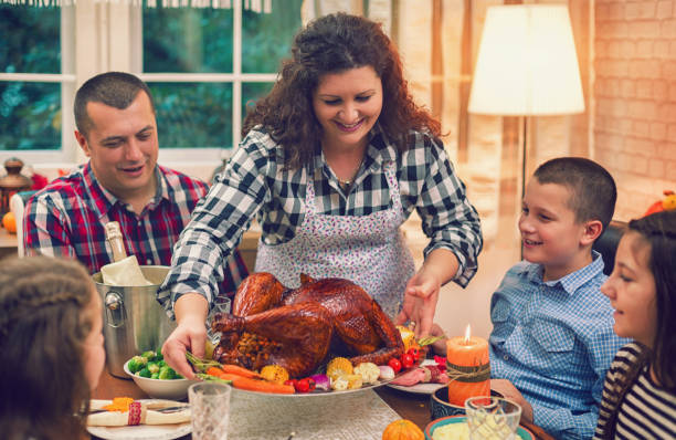 istock Young Mother Serving Stuffed Turkey for Thanksgiving Dinner 1277207597