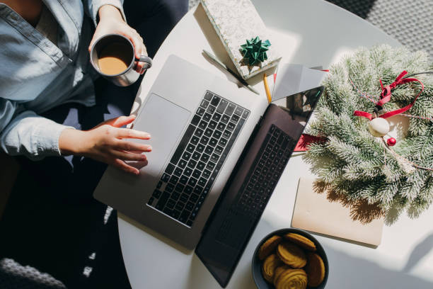 comunicare con i propri cari a natale: una donna anonima che usa il suo pc portatile in un ambiente natalizio - holiday vacation foto e immagini stock