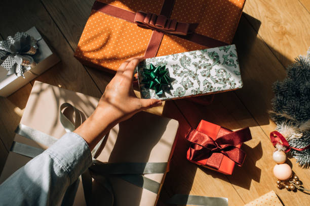 hand of a woman holding a wrapped christmas present, an overhead view - hand wrap imagens e fotografias de stock