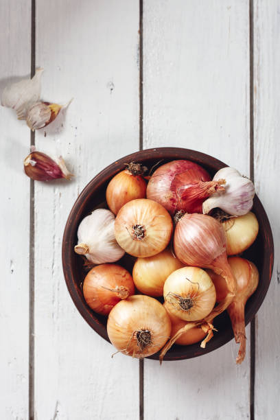 istock Onions and garlic on a white wooden background. 1277210801