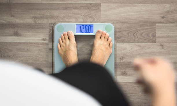 istock Woman's feet stepping on weighing scale. 1277213471