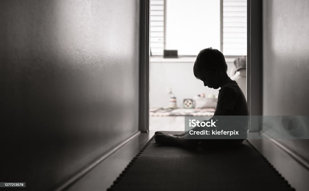 Lonely sad boy at home Sad boy sits alone. Child Stock Photo