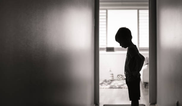 ragazzo triste in piedi da solo nel corridoio - sadness child little boys loneliness foto e immagini stock
