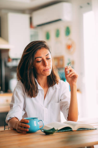 istock Woman Reading a Book in Cozy Environment With Cigarette in Hand 1277214980